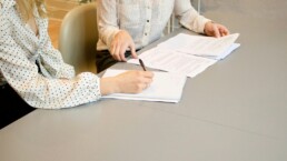 Un incontro tra titolare di PMI e team di un'agenzia di comunicazione che discute un piano di lavoro